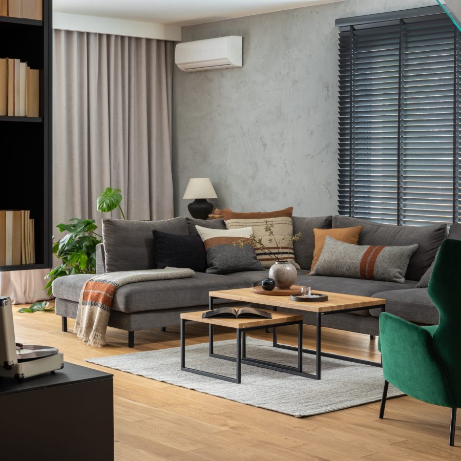 Stylish composition of living room interior with corner grey sofa,  design furniture and minimalist personal accessories. Book shelf. Modern home decor. Template.